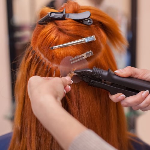 Long red hair with extensions being fitted