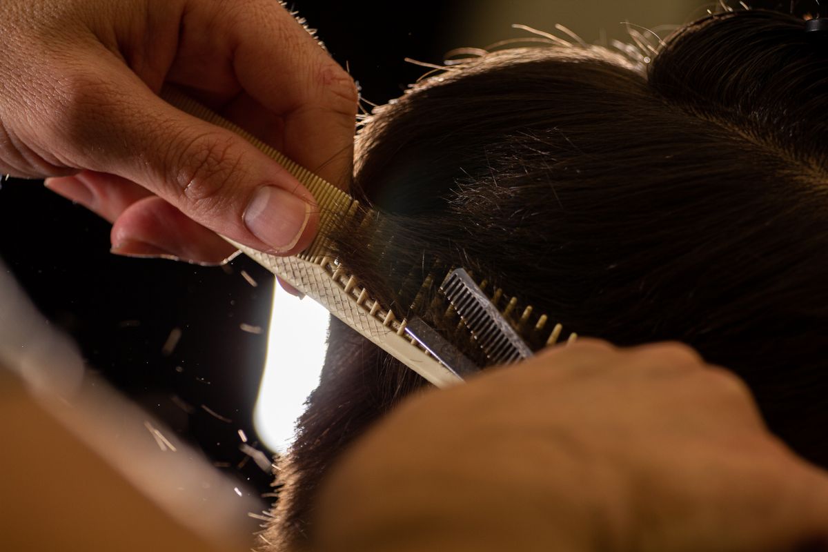 Stylist trimming hair with scissors and comb